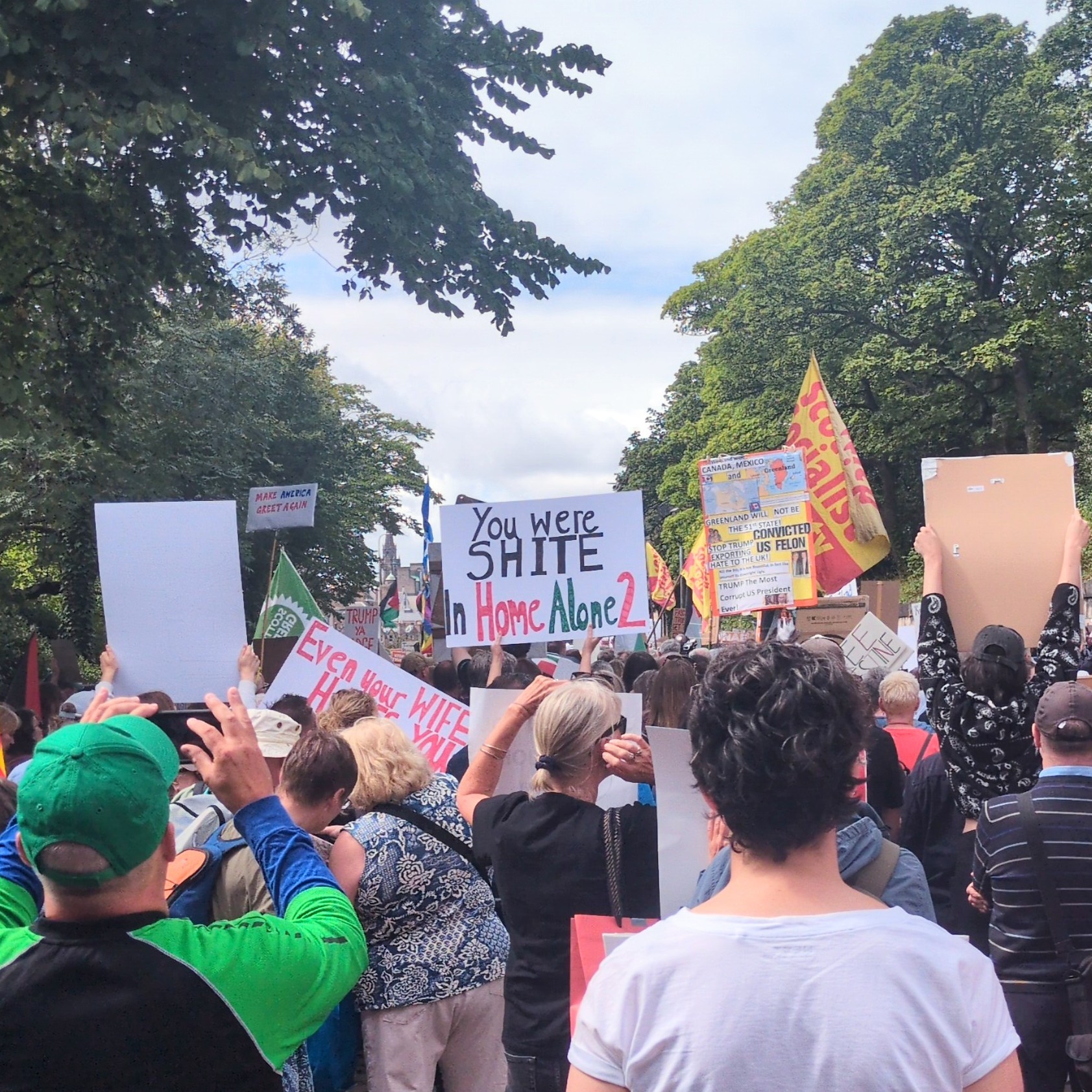Photo of a crowd of protestors, focused on a sign in the centre reading "you were shite in Home Alone 2"