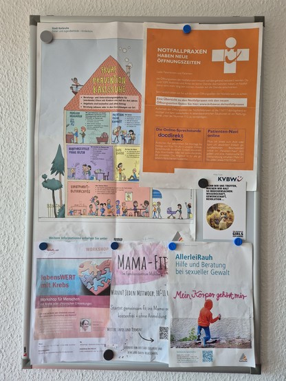 Eine Magnettafel mit Informationen zu Notfallpraxen, einer Info zu einer Organisation, an die eins sich bei sexualisierter Gewalt wenden kann usw. Dazwischen gemogelt eine Karte der "Präraffaelitischen Girls", auf der steht, wenn wir uns treffen, machen wir so Mädchensachen - Wissenschaft, Gewerkschaft, Revolution. 