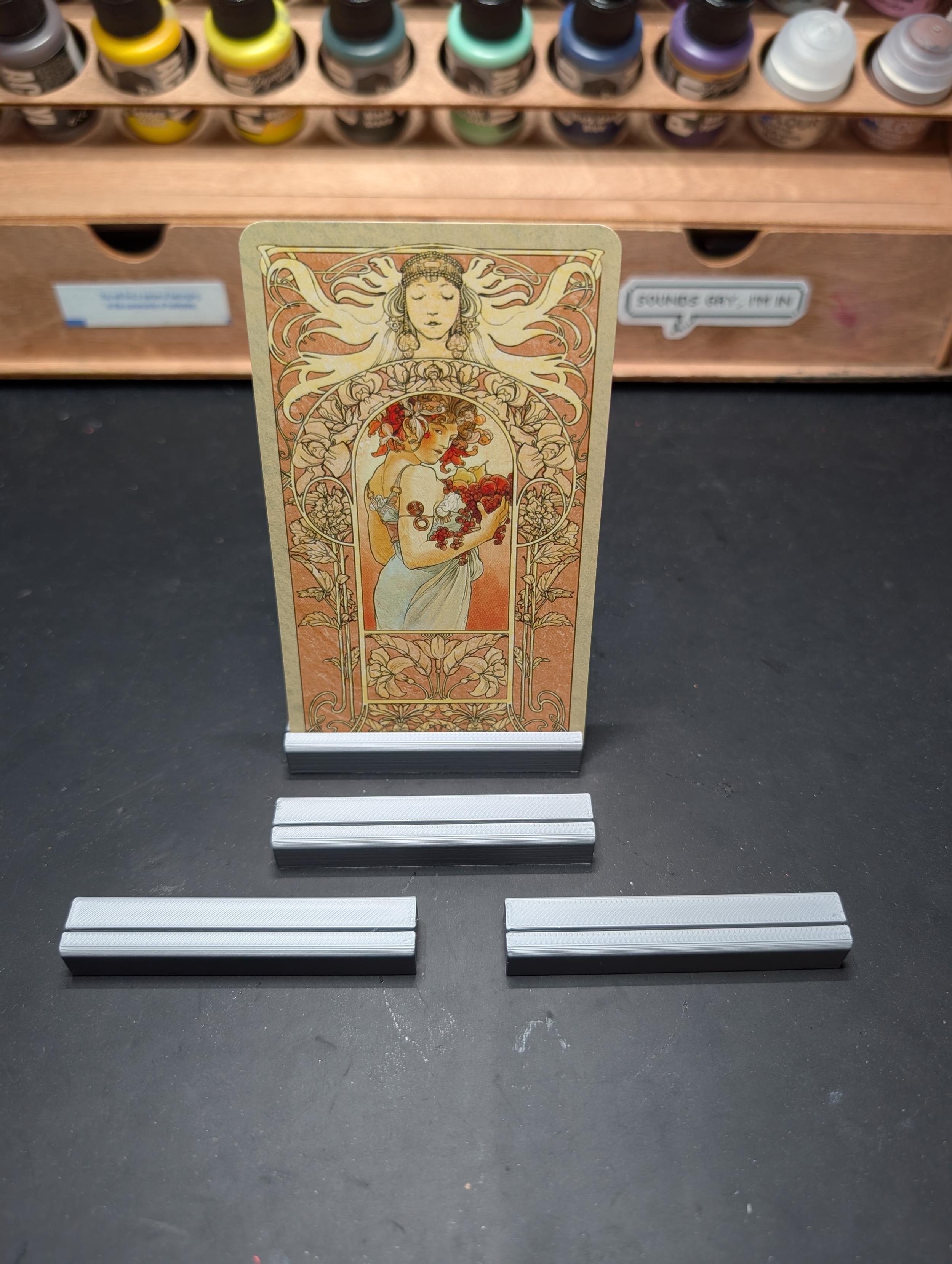 Photo of 4 grey card holders, one of which has a tarot card in it.