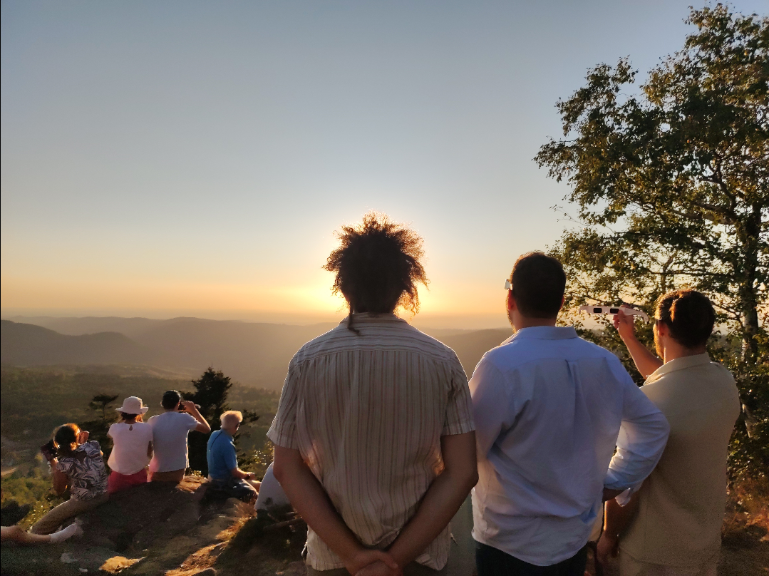 un groupe de personnes observant l'éclipse, au centre, une touffe de cheveux cache l'éclipse à contre-jour, avec ses cheveux frisés qui font rayonner la lumière autour de sa tête.